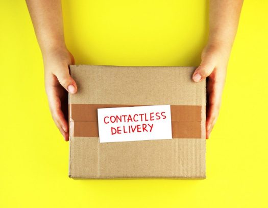 a pair of hands holding a box that says 'contactless delivery' on a yellow background