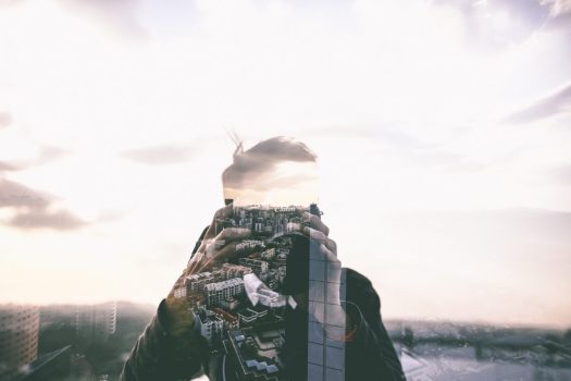 a double exposure photograph that shows the photographer and an image of the city overlaid