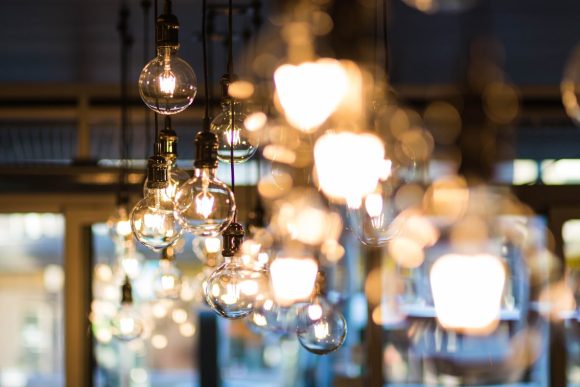 A bright bokeh effect photo of Edison light bulbs in the foreground and blurry bright lights in the background.