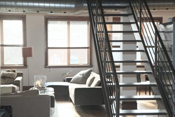A condo living room with metal stairs and neutral colors furnishing