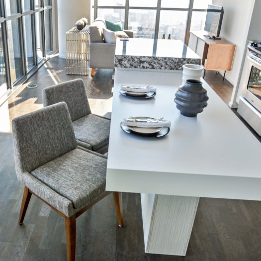 Naveed's living room with a dining table, two chairs, and two place settings. In the background is a small couch, console with TV, and a view of the city from his condo.